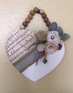 a heart shaped decoration hanging on the wall with musical notes and flowers attached to it