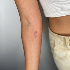 a woman's arm with a small flower tattoo on the left side of her body