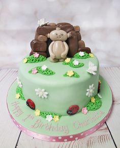 a green birthday cake with a monkey and ladybug on the top is sitting in front of it