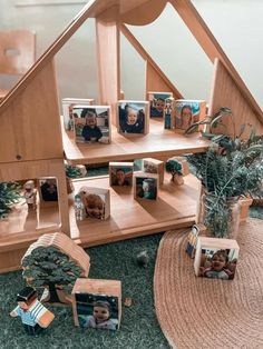 a doll house with pictures and potted plants on the floor in front of it