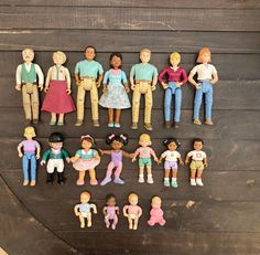 a group of dolls standing next to each other on a wooden surface with one holding the hand of another doll