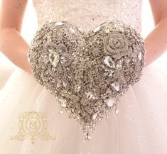 a woman in a wedding dress holding a heart shaped brooch