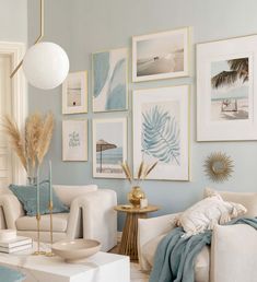 a living room filled with white furniture and pictures on the wall above it's coffee table