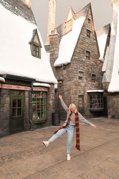 a woman standing in front of a building with snow on the roof and chimneys