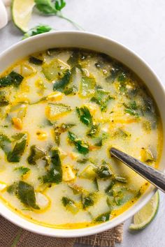 a white bowl filled with soup on top of a table next to sliced limes