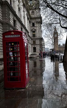 a red phone booth sitting on the side of a street