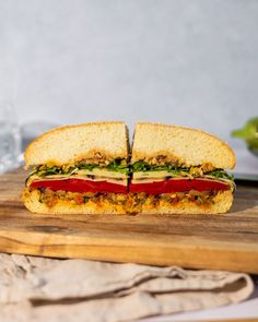 a cut in half sandwich sitting on top of a wooden cutting board