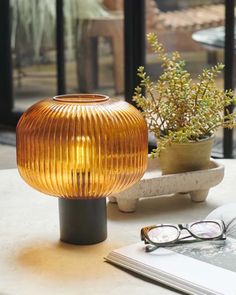 a table topped with a lamp next to a book and eyeglasses on top of it