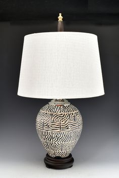 a table lamp with a white shade on it's base and an abstract design