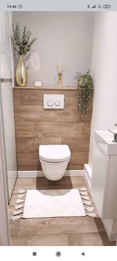 a white toilet sitting inside of a bathroom next to a wooden counter top and sink