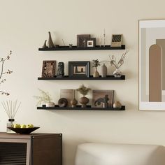 a living room filled with furniture next to a wall mounted art piece on a white wall