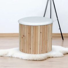 a wooden stool sitting on top of a hard wood floor next to a white rug