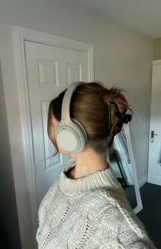 a woman with headphones on her ears looking at herself in front of a mirror