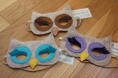 three owl masks sitting on top of a wooden floor next to each other with tags around them