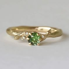 a gold ring with green and white stones