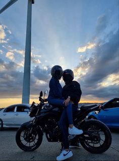 two people are sitting on a motorcycle in the parking lot