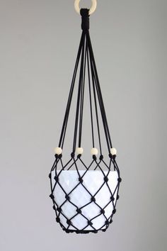 a black and white hanging pot holder with three lights on it's sides, in front of a gray wall