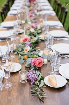 a long table with plates and flowers on it