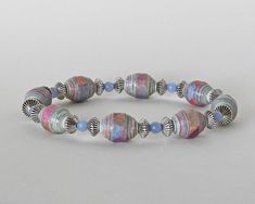 a bracelet made out of glass beads on a white surface with spacers in the middle