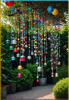 a colorful wind chime hanging from a tree in front of some potted plants