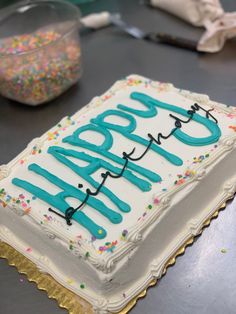 a birthday cake with the words happy birthday written in blue frosting on top and sprinkles around it