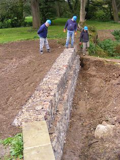 three people are standing on a stone wall