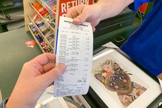 a person is holding up a receipt in front of a store clerk's desk