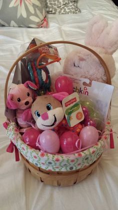 a basket filled with toys on top of a bed next to a stuffed animal and other items