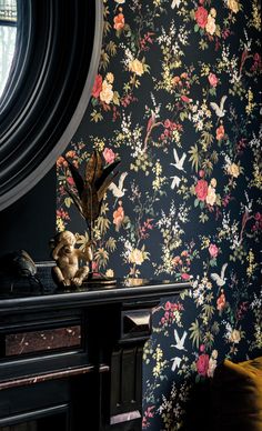 a wallpapered room with flowers and birds on the wall next to a mirror