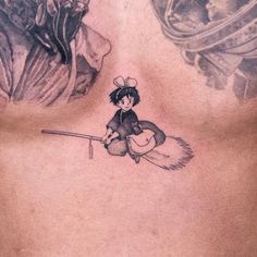 the back of a man's chest with a tattoo on it and a girl holding a broom