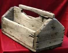 an old wooden box sitting on top of a red cloth