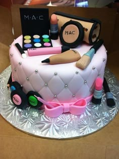 a pink cake with makeup and cosmetics on it