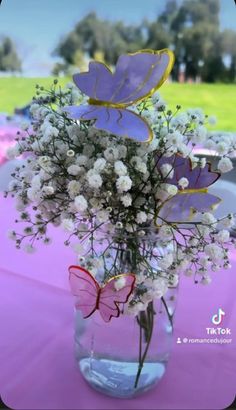 a vase filled with white flowers and purple butterflies