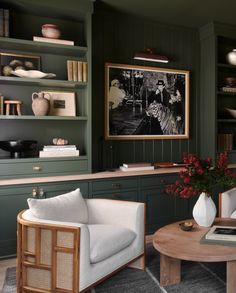 a living room filled with furniture and bookshelves next to a painting on the wall