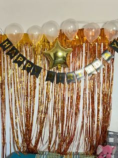 balloons and streamers are hanging from the ceiling in front of a birthday party backdrop