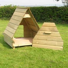 a dog house made out of wooden pallets in the middle of a grassy field