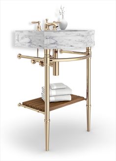 a bathroom sink with gold faucet and white marble counter top next to a wooden shelf