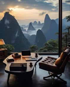 a desk with a laptop on it in front of a large window overlooking the mountains