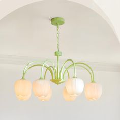 a green chandelier hanging from the ceiling with four lights on it and an arch in the background