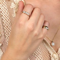 a close up of a person wearing a ring with pearls on it's fingers