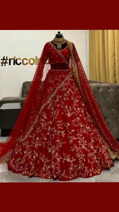 a red bridal gown on display in front of a couch