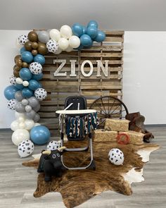 a baby's rocking chair with balloons and other decorations in front of a wooden sign