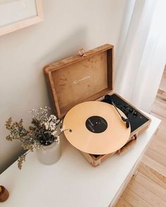 an old record player sitting on top of a table next to a potted plant