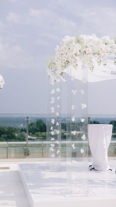 an outdoor ceremony setup with white flowers and butterfly decorations on the top of a building