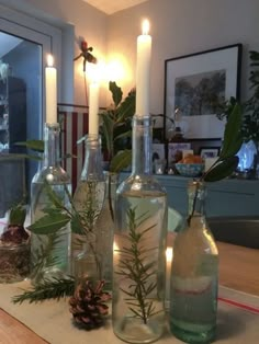 several bottles with plants in them on a table next to candles and other items that are lit up