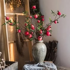 a vase filled with red flowers sitting on top of a table next to a window