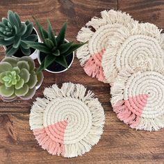 three woven coasters with succulent plants in the middle on a wooden table