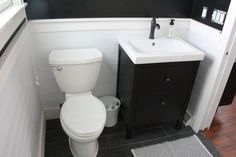 a white toilet sitting next to a sink in a bathroom under a black and white wall