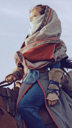 a man riding on the back of a horse with a scarf around his neck and head