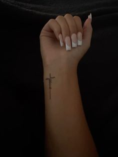 a woman's arm with a cross tattoo on it